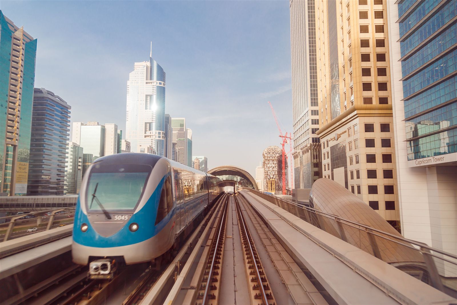 A metro train on an elevated track between city towers
